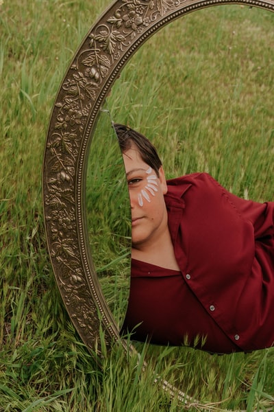 穿着红外套的女人躺在绿色的草地上